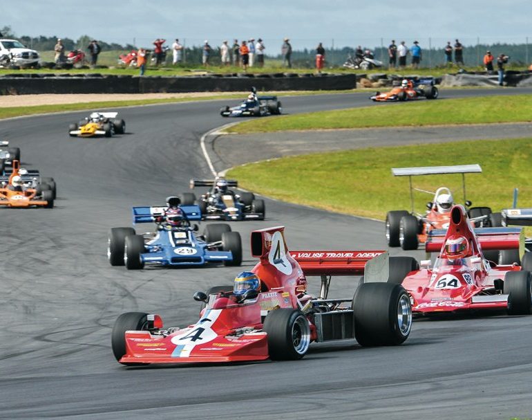 As usual, veteran Ken Smith is out front of the F5000 field in his Lola T430, chased by the Lola T400 of Mark Dwyer and the rest of the field. Photo: Ian Welsh