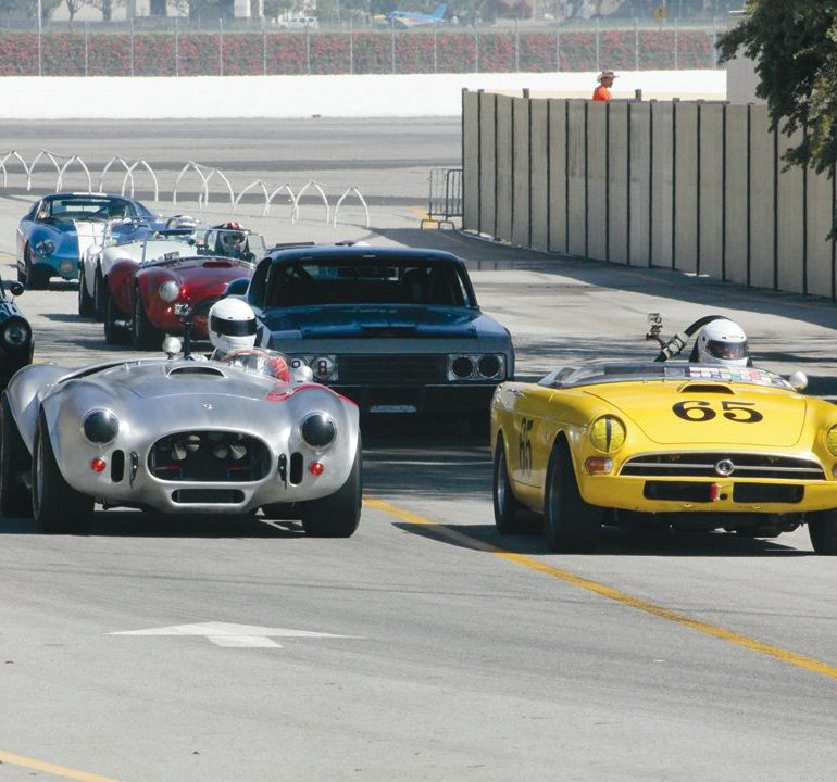 Tom Sakai in his 1965 Sunbeam Tiger (#65) leads the field under the bridge during Saturday morning. Photo: Craig R. Edwards