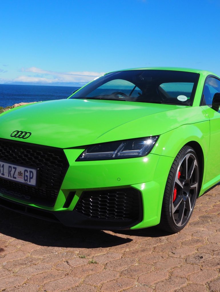 Green 2022 Audi TT RS on cobblestone street near ocean