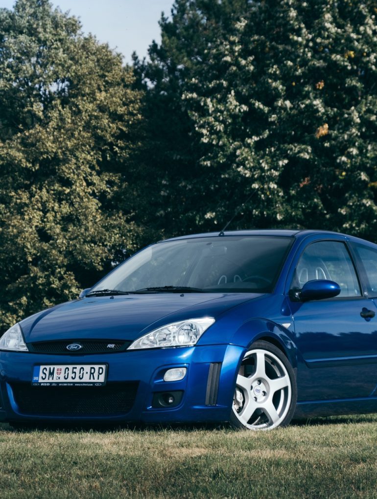 Blue Ford Focus RS on grassy field with trees in background