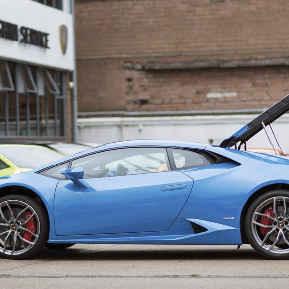 Man inspecting the engine bay of a blue Lamborghini Huracan