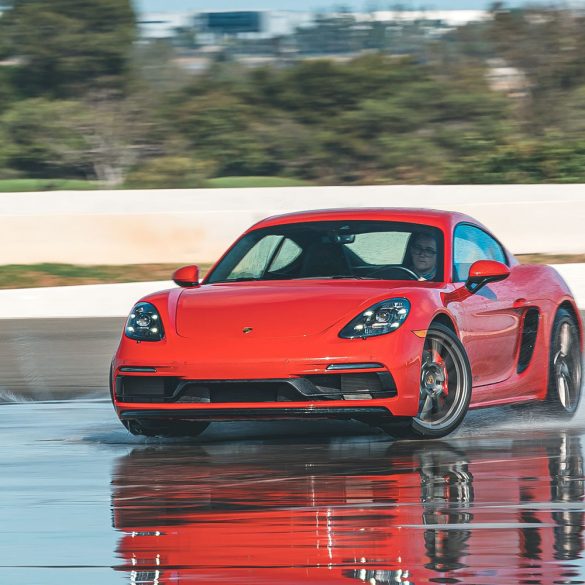 Red Porsche 718 Cayman GTS sliding on a wet track