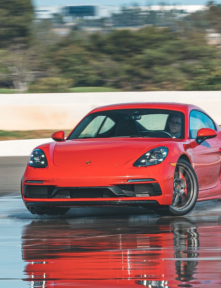 Red Porsche 718 Cayman GTS sliding on a wet track