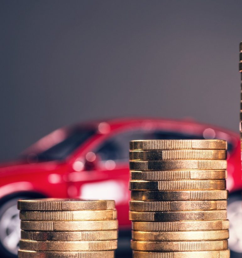 Coins stacked in front of a red car