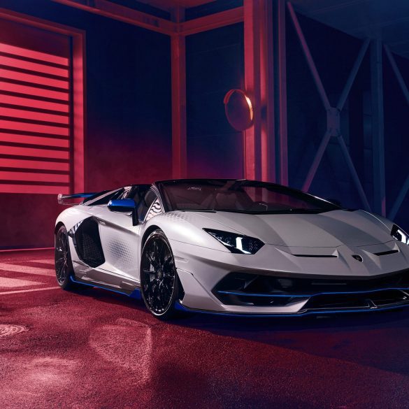 Front angled shot of a silver Lamborghini Aventador SVJ Roadster Xago Edition against a darkened background.