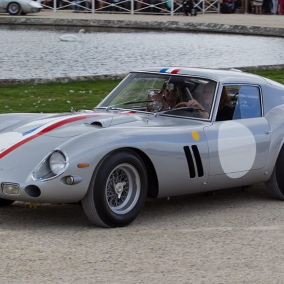 Front-angled view of a silver Ferrari 250 GTO with a red, white and blue stripe running from the hood to the boot.