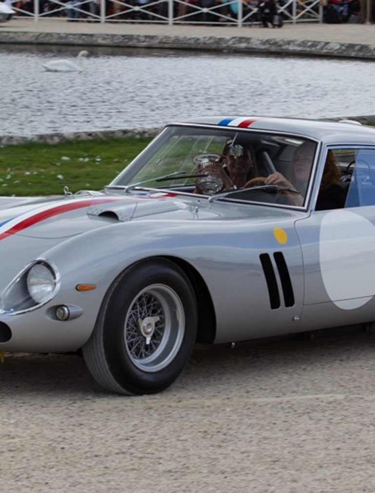 Front-angled view of a silver Ferrari 250 GTO with a red, white and blue stripe running from the hood to the boot.