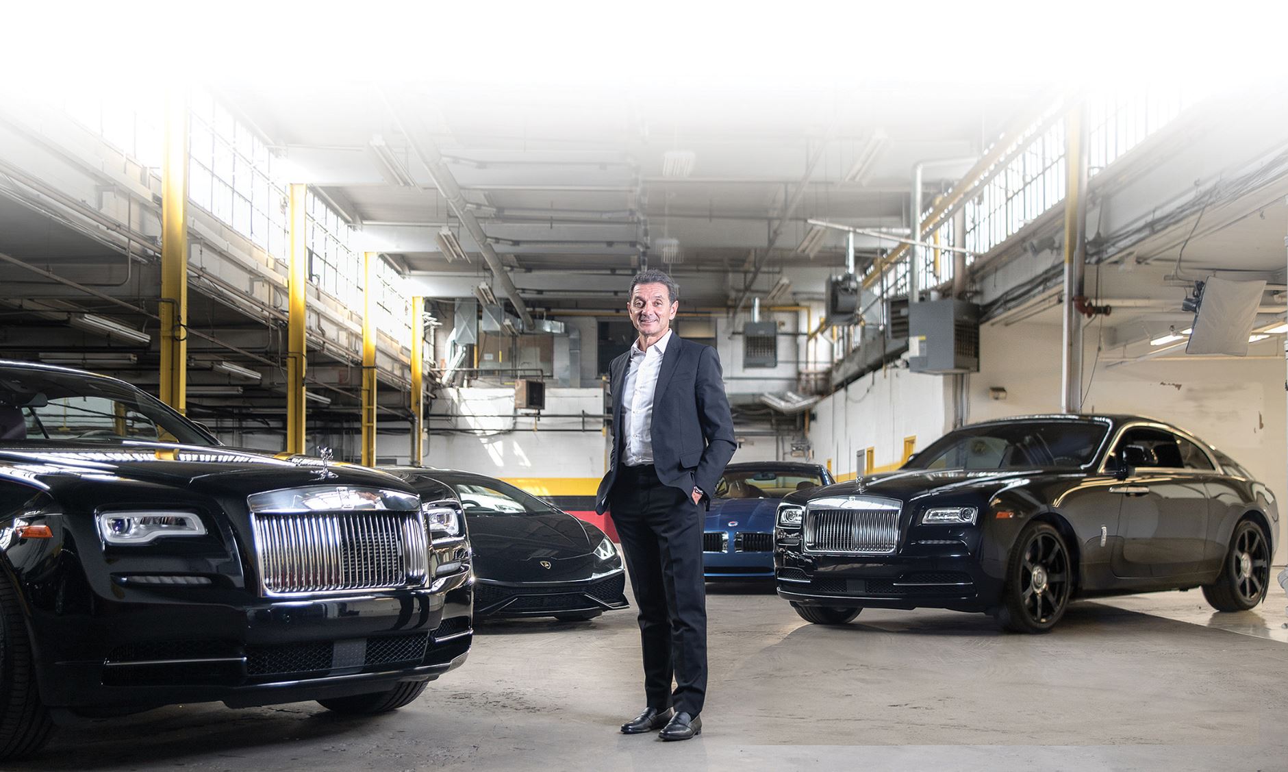 Man stands in front of a fleet of super sports cars